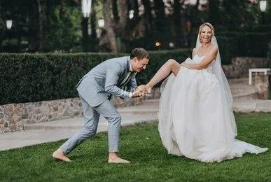Groom playfully posing with his bride on the lawn