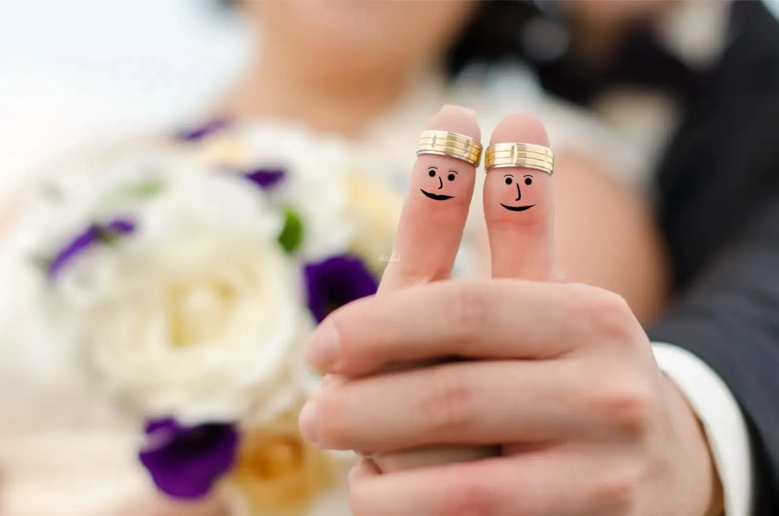 Wedding rings with smiley faces drawn on thumbs
